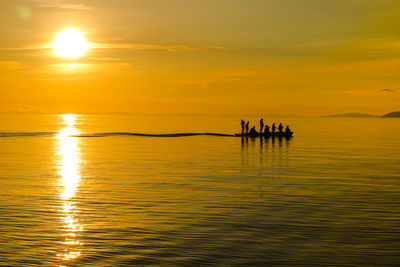 Silhouette people on boat in sea against sky during sunset