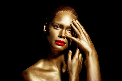 Portrait of woman with golden glitter make-up against black background
