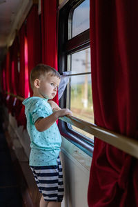 Side view of boy standing by window