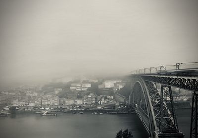 Bridge over river in city against sky