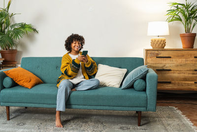 Young woman sitting on sofa at home