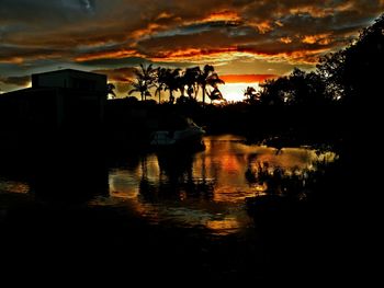 Silhouette of trees against cloudy sky at sunset