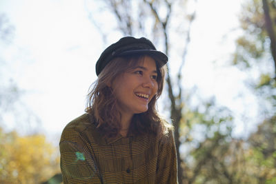 Portrait of smiling young woman against trees