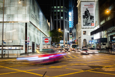 Light trails on city street by buildings at night