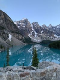Scenic view of moraine lake by mountains against clear blue sky