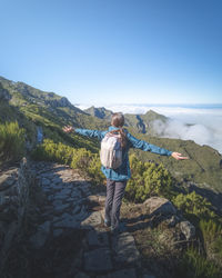 Rear view of man standing on mountain against clear sky