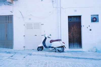 Motor scooter parked on street against building