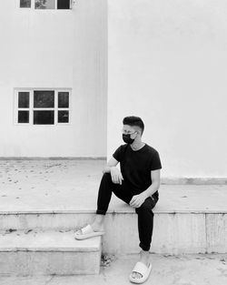 Full length of young man wearing sunglasses against wall