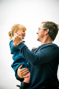 Side view of father and daughter dancing against white sky