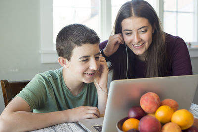 Happy mother and son using laptop on table at home