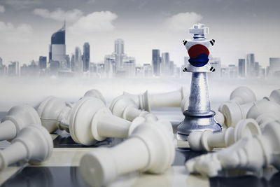 Digital composite image of chess pieces with flag against buildings in city