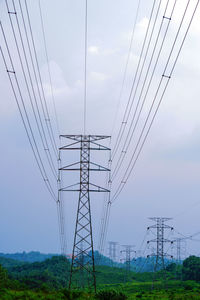 Low angle view of electricity pylons against sky