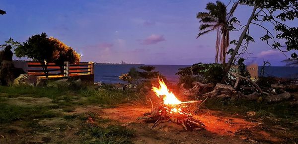 Bonfire on beach against sky at dusk