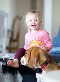 Portrait of smiling cute girl sitting on bed at home