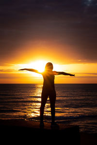 Silhouette woman standing on beach during sunset