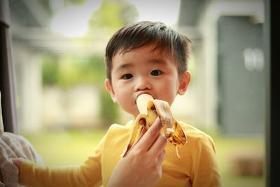 Cropped hand of mother feeding banana to cute son