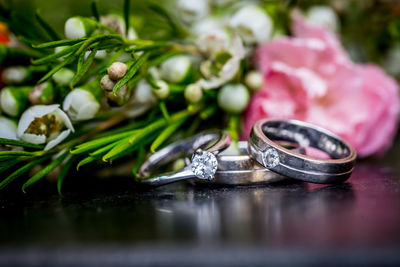 Close-up of wedding rings with bouquet on table