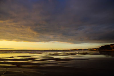 Scenic view of sea against dramatic sky during sunset