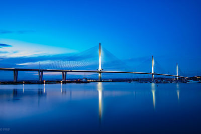 Illuminated bridge over river at night