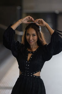 Portrait of young woman standing against wall
