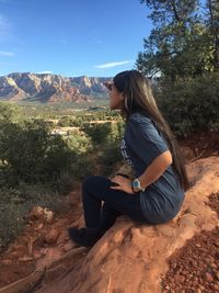 Side view of woman sitting on rock