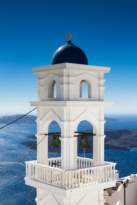 Bell tower against sea and blue sky