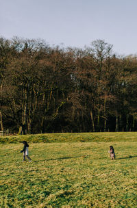 People on field by trees against sky