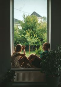 Rear view of woman looking through window