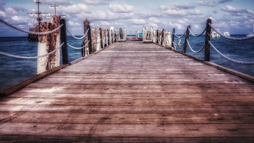 Wooden pier in sea against sky