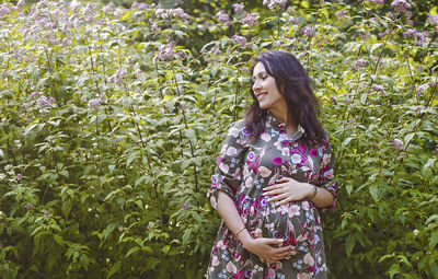 Young woman standing against plants