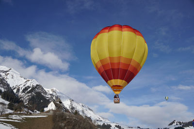 Hot air balloons flying over snowcapped mountains against sky