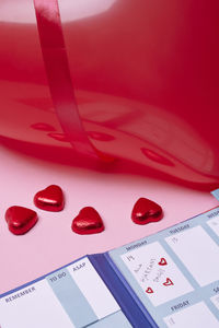 Heart-shaped candies and calendar on pink background