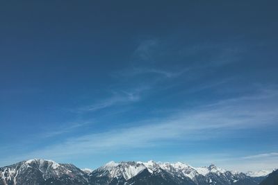 Snow covered mountains against blue sky