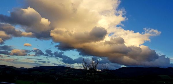 Scenic view of clouds over mountains against blue sky