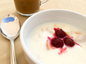 High angle view of cherries in yogurt with coffee and spoon on table