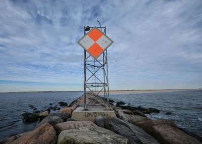 Lighthouse by sea against sky