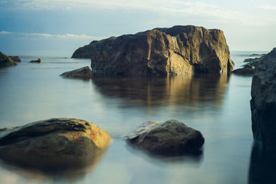 Rocks on sea shore against sky