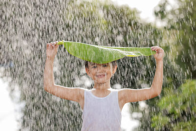 Portrait of smiling woman standing on wet plant
