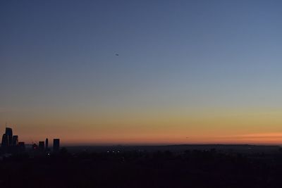 Silhouette city against sky during sunset