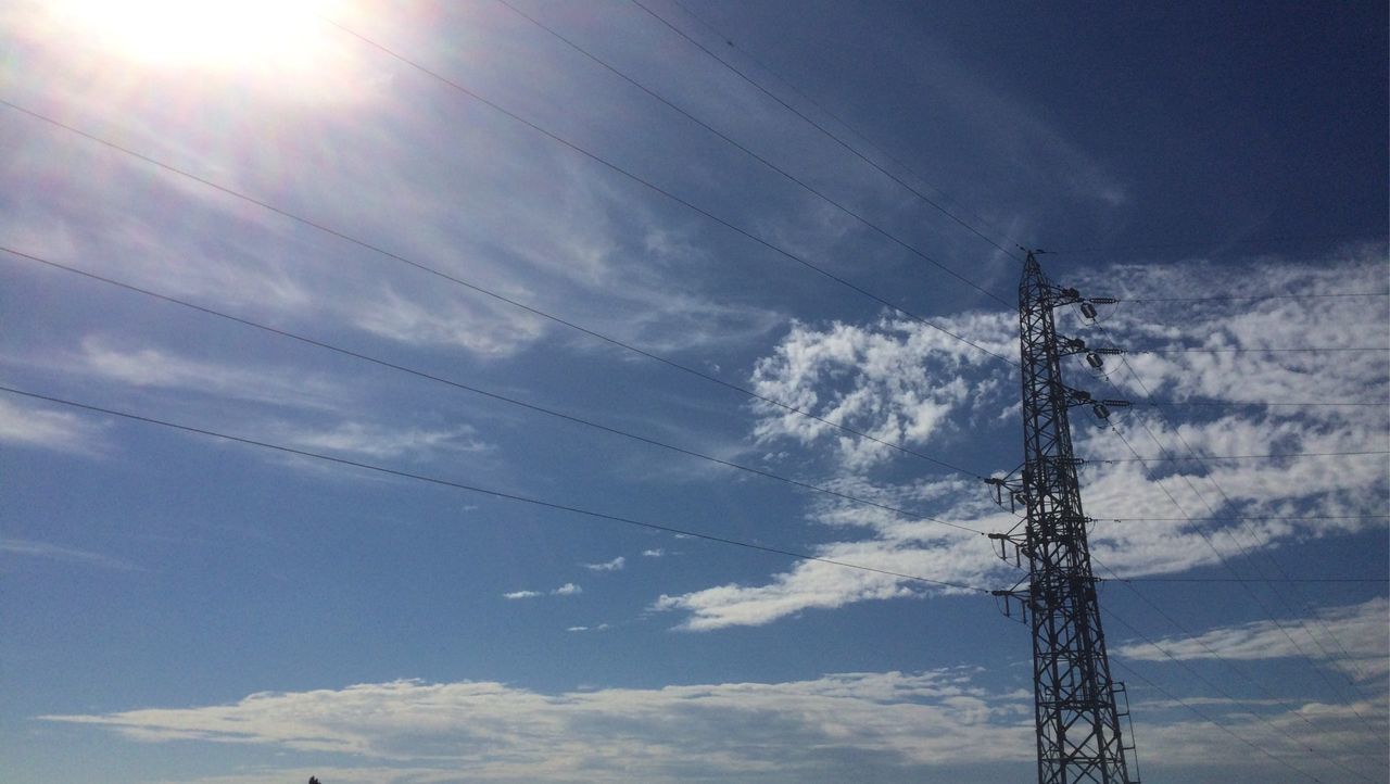 low angle view, electricity, power line, electricity pylon, power supply, fuel and power generation, connection, sky, technology, cable, sun, cloud - sky, blue, sunlight, silhouette, nature, sunbeam, power cable, outdoors, no people