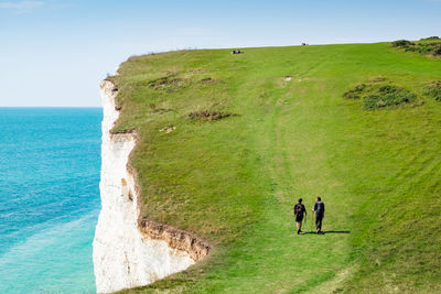 People on shore by sea against sky