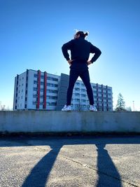 Full length of man jumping in city against clear sky