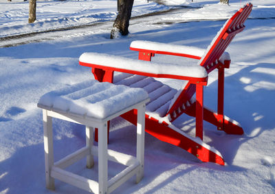 Red adirondack chair along the frozen shore in winter snow