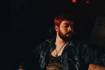 Man looking away while sitting in darkroom