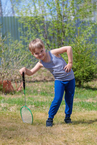 A fair-haired child plays badbinton on the lawn
