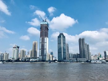 Modern buildings in city against cloudy sky