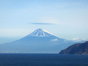 Scenic view of sea and snowcapped mountain against sky