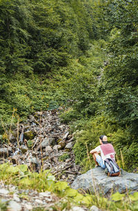 Rear view of woman sitting on rock