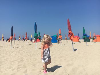 Girl walking at beach against clear sky