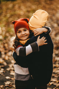 Happy cheerful children in warm clothes have fun walking running in autumn park playing with leaves